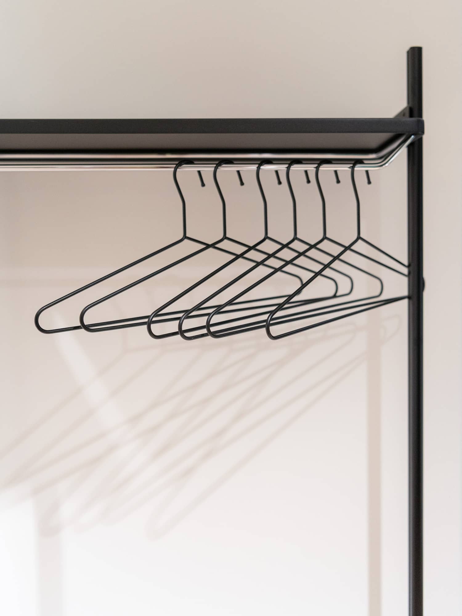 An einer minimalistischen Garderobe h&auml;ngen viele d&uuml;nne Kleiderb&uuml;gel
